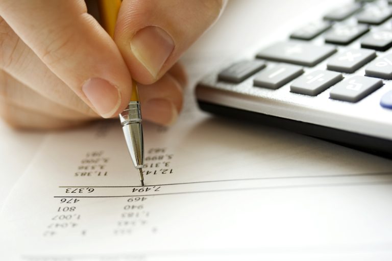 person writing with pencil and part of keyboard