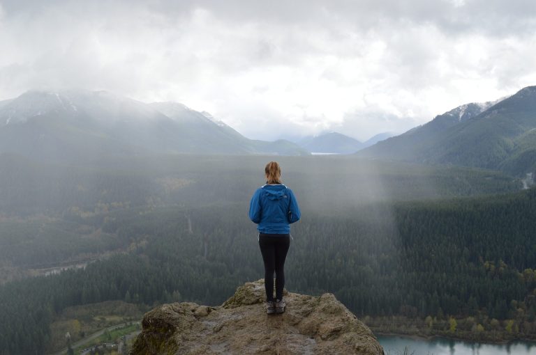 Woman standing on rock looking over foggy valley